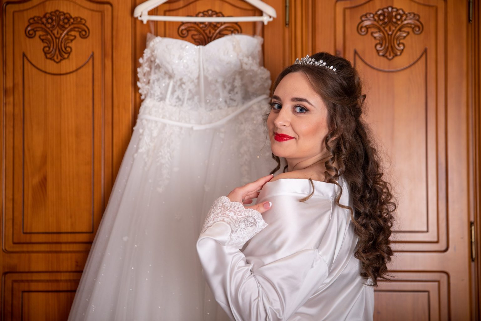 Novia durante los preparativos junto a su vestido de boda