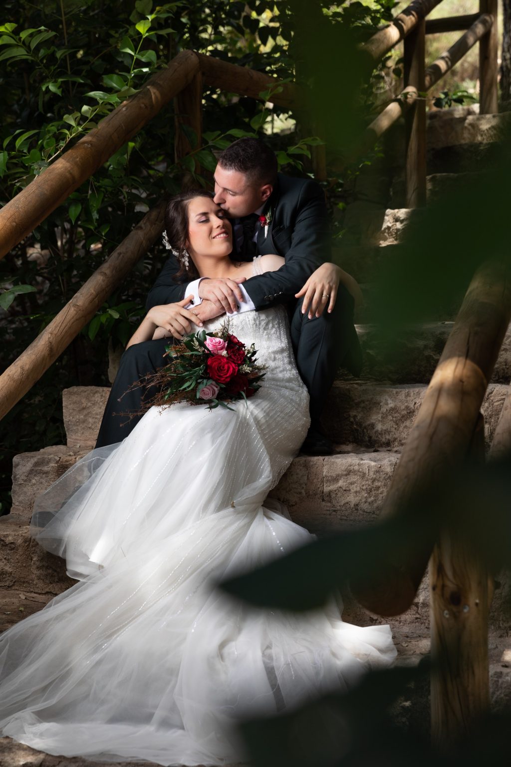 Novios compartiendo un momento íntimo bajo un árbol