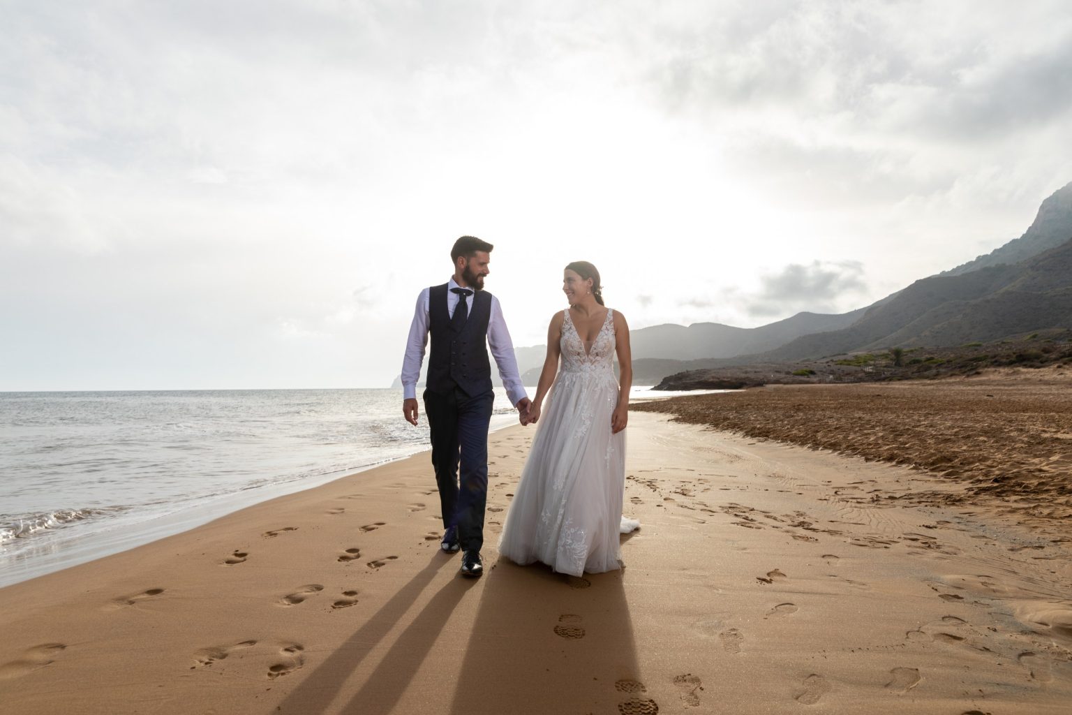 Pareja de recién casados caminando por una playa del Mediterráneo
