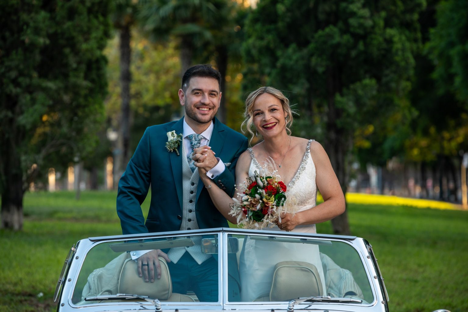 Pareja de recién casados celebrando en un coche clásico