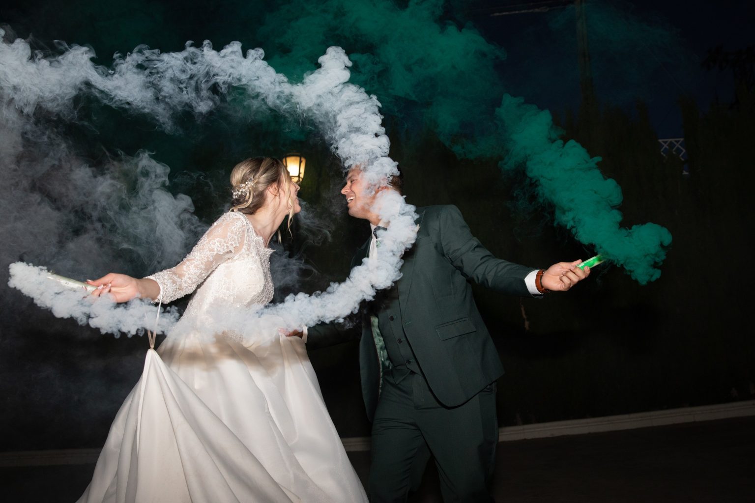 Pareja de novios celebrando entre humo de colores durante la fiesta