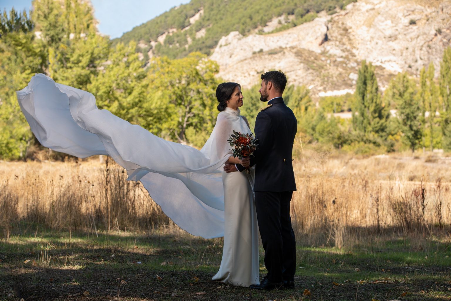 Pareja de recién casados en un paisaje rural con el vestido al viento