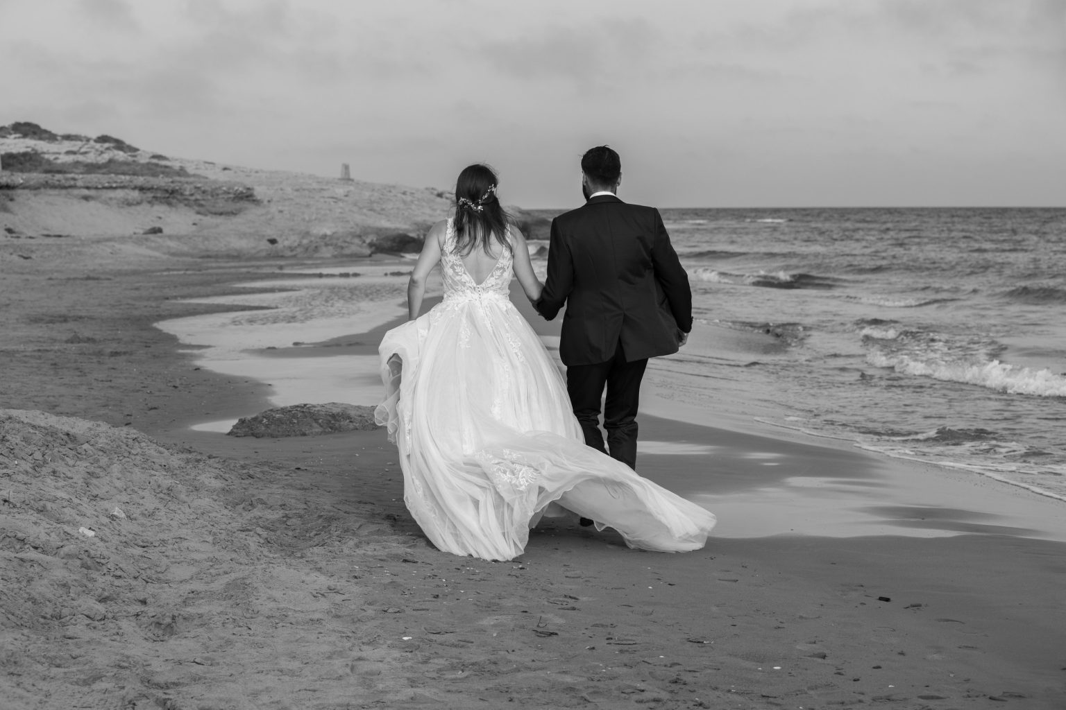 Pareja de recién casados junto al mar y un edificio histórico
