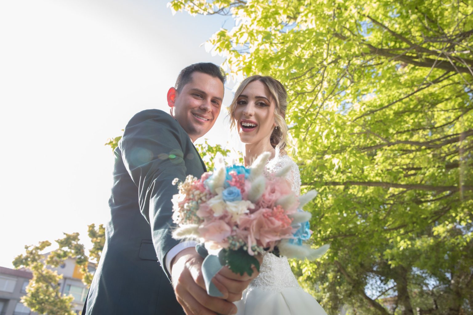 Pareja de novios riendo y mostrando su ramo de flores