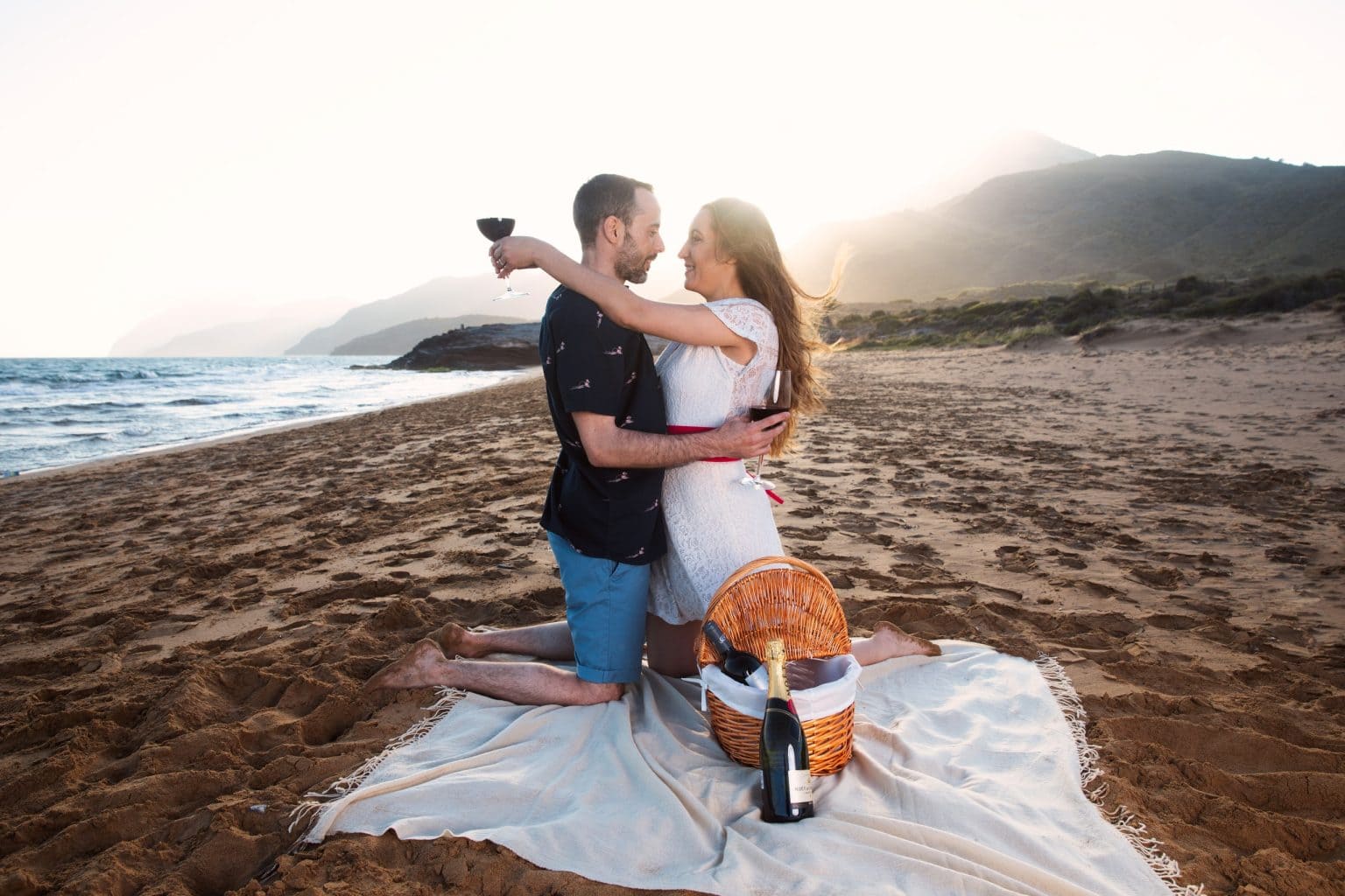 Pareja abrazada durante un picnic de preboda en la playa