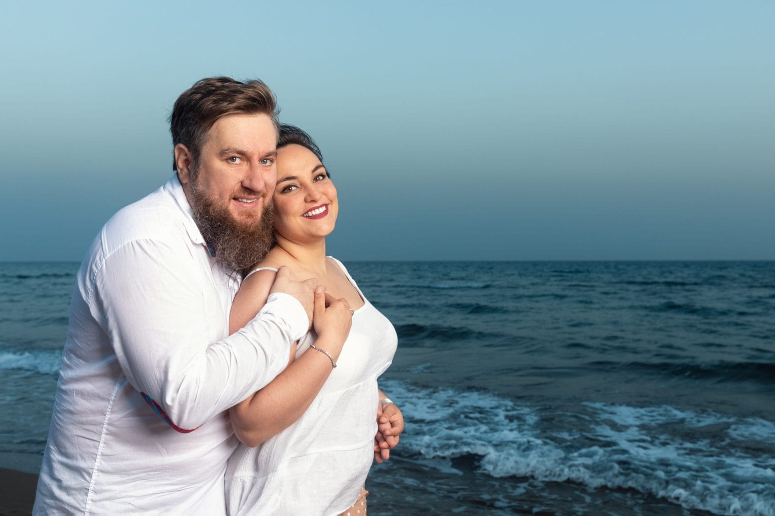 Pareja riendo junto al mar durante su preboda