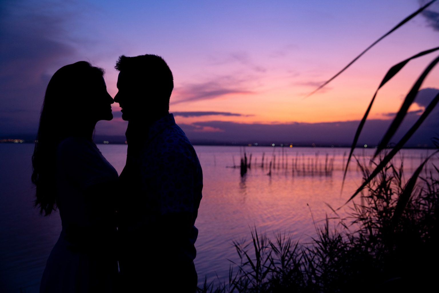 Silueta de una pareja frente a un atardecer violeta